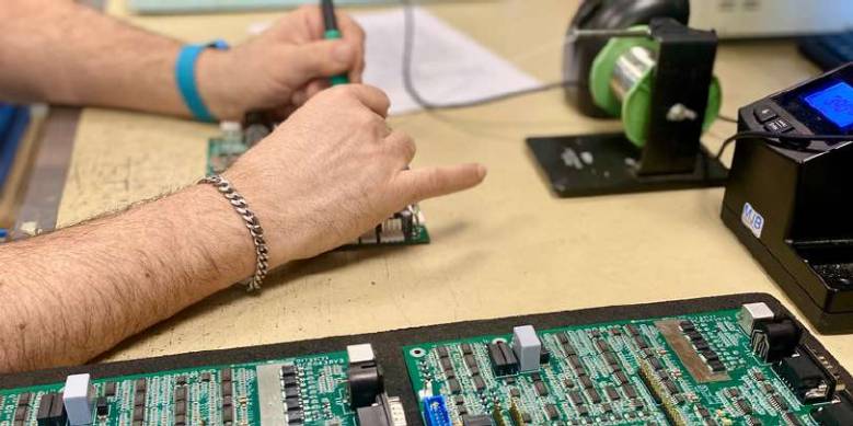 Une personne qui soude un circuit numérique